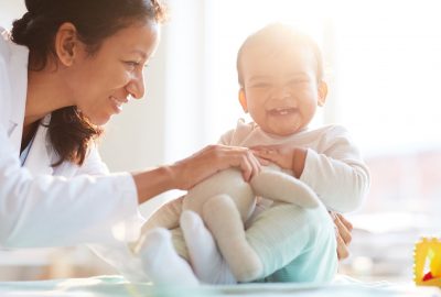 Smiling nurse having fun together with child they playing with toys during her visit